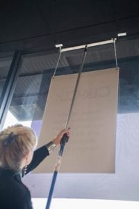 A store owner using Ceiling Outfitter's easy-up Interior signage hanging system.